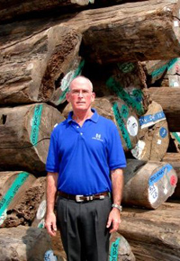 Gib McIlvain in front of Teak logs