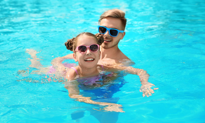 father helping daughter learn how to swim