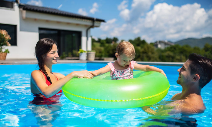 happy parents in pool with young daughter
