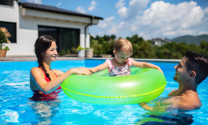parents in swimming pool with toddler and green tube