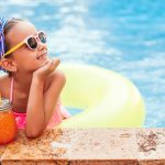 fashionable little sunglasses girl with drink and pool float posing